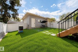 Expansive lawn with stepping stone pathway, white privacy fencing, and wood-finish exterior staircase with black metal railings - 