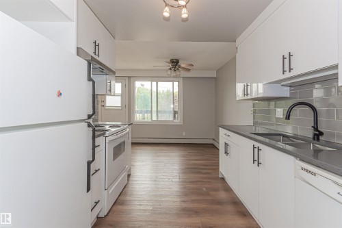 Kitchen featuring white cabinetry, dark countertops, and a gray subway tile backsplash - Edmonton, AB - Indoor Photo Showing Kitchen With Double Sink