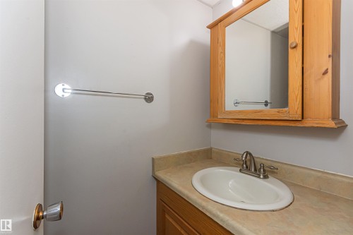 Bathroom vanity featuring a light wood-finish cabinet, integrated sink, and an overhead wood-framed medicine cabinet with mirror - Edmonton, AB - Indoor Photo Showing Bathroom