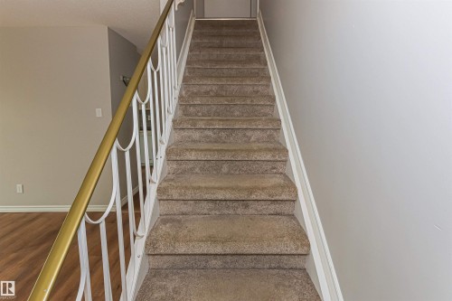 Carpeted staircase featuring a decorative metal railing with a brass-finish handrail - Edmonton, AB - Indoor Photo Showing Other Room