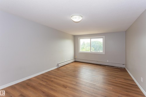 Light gray walls frame a room featuring wood-finish flooring - Edmonton, AB - Indoor Photo Showing Other Room