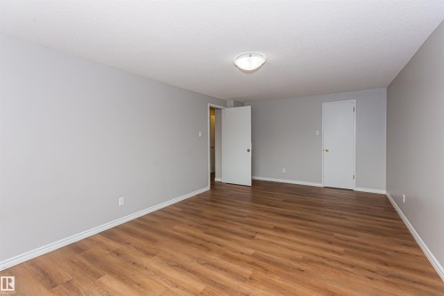 Spacious interior room featuring wood-finish flooring, light gray wall paint, and white trim - Edmonton, AB - Indoor Photo Showing Other Room