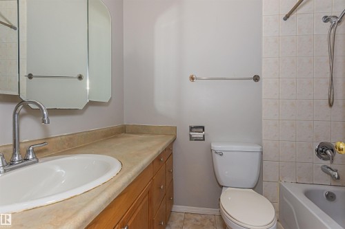 Bathroom vanity with a tan countertop and integrated sink, chrome faucet, and wood-finish cabinetry - Edmonton, AB - Indoor Photo Showing Bathroom