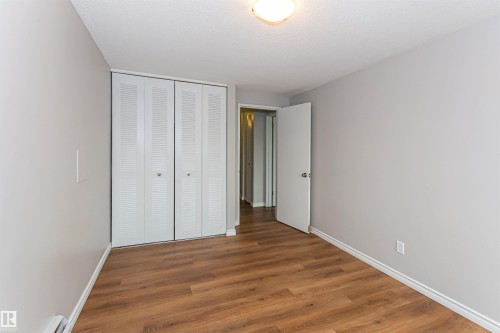 Interior room featuring wood-finish flooring, light grey painted walls, white baseboards, and a ceiling-mounted light fixture - Edmonton, AB - Indoor Photo Showing Other Room