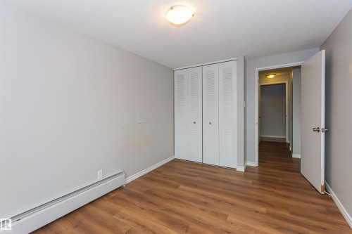 Spacious room featuring wood-finish flooring, light grey painted walls, white trim, and a ceiling-mounted light fixture - Edmonton, AB - Indoor Photo Showing Other Room