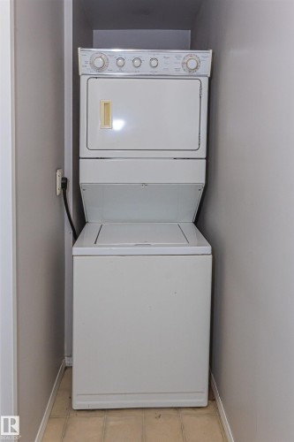 Stacked laundry appliances within a dedicated alcove - Edmonton, AB - Indoor Photo Showing Laundry Room