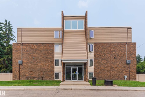 Multi-story building featuring a brick facade with tan siding accents and a prominent central entrance - Edmonton, AB - Outdoor