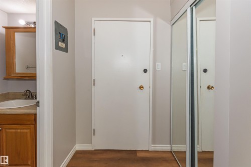 Interior entryway featuring wood-finish flooring and a white door with a brass-toned doorknob - Edmonton, AB - Indoor Photo Showing Other Room