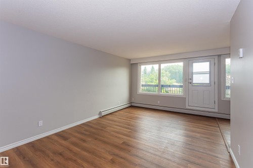Living area featuring wood-finish flooring, light gray wall paint, and white baseboards - Edmonton, AB - Indoor Photo Showing Other Room
