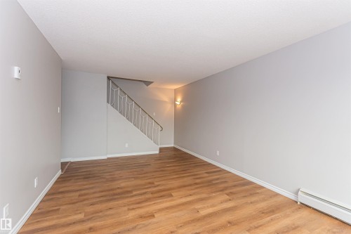 Expansive interior space featuring wood-finish flooring, light gray walls, and white baseboards - Edmonton, AB - Indoor Photo Showing Other Room