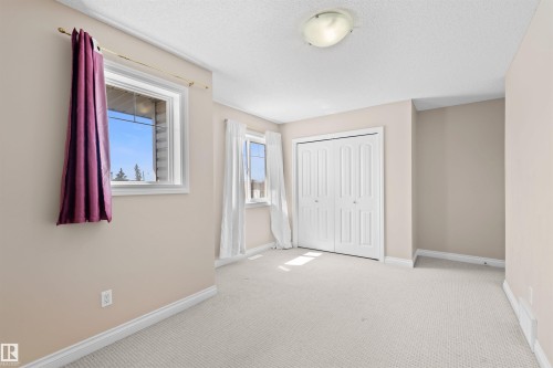 Neutral carpet flooring, bi-fold closet doors, white trim, and a semi-flush mount ceiling light fixture - 15504 102 Avenue Nw, Edmonton, AB 