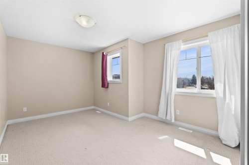 Neutral tone wall paint with white trim, light-colored carpet flooring, and a semi-flush ceiling light fixture - 15504 102 Avenue Nw, Edmonton, AB 
