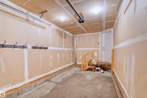 Attached lighting fixtures, unpainted drywall, concrete flooring, wooden interior stairs, and a paneled interior door - 15504 102 Avenue Nw, Edmonton, AB 