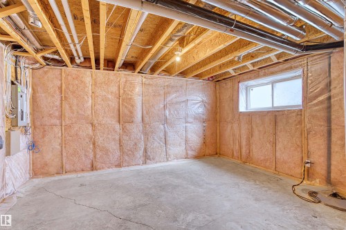 Unfinished basement with concrete flooring, exposed wood ceiling joists, insulated walls, and an egress window - 15504 102 Avenue Nw, Edmonton, AB 