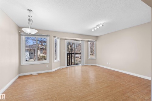 Wood-finish flooring with a multi-pane window, a sliding glass door, and neutral-toned walls - 15504 102 Avenue Nw, Edmonton, AB 