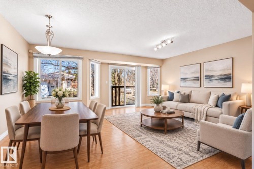Open-concept living and dining areas featuring wood-finish flooring, bay windows, track lighting, and a sliding glass door - 15504 102 Avenue Nw, Edmonton, AB 