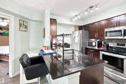 Kitchen featuring dark wood-finish cabinetry, stainless steel appliances, a dark stone countertop island, and track lighting - 