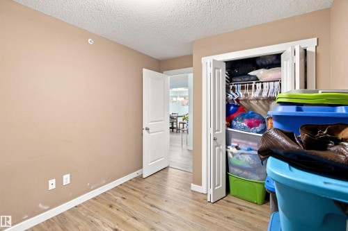 Wood-finish flooring, neutral wall tones, white trim, and a bi-fold closet door - #413 18126 77 St Nw, Edmonton, AB 