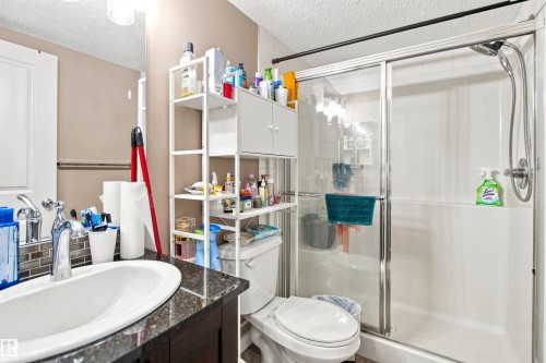 Vanity with an oval undermount sink, mosaic tile backsplash, and dark granite-style countertop - #413 18126 77 St Nw, Edmonton, AB 