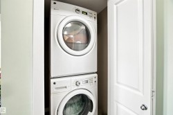 Stacked washer and dryer unit, white paneled door, and light wall finishes - 