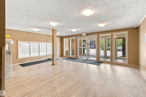 Entrance foyer with wood-finish flooring, flush mount lighting, and large window panels - #413 18126 77 St Nw, Edmonton, AB 