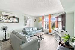 Light wood-finish flooring, wall-mounted air conditioning unit, white trim windows, and a built-in media console - 