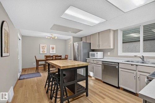 Contemporary kitchen featuring wood-finish flooring, recessed lighting, stainless steel appliances, and a butcher block island - 17919 78 Avenue Nw, Edmonton, AB 