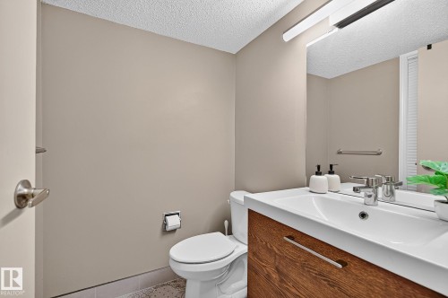 Floating vanity with wood-finish cabinetry, integrated sink, and brushed nickel faucet - 17919 78 Avenue Nw, Edmonton, AB 