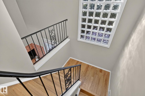 Hardwood flooring, painted walls, black wrought iron railings with decorative scrollwork, and a glass block window - 17919 78 Avenue Nw, Edmonton, AB 
