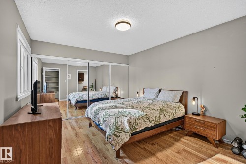 Hardwood flooring, mirrored closet doors, a rectangular window with white trim, and a flush-mount ceiling light - 17919 78 Avenue Nw, Edmonton, AB 