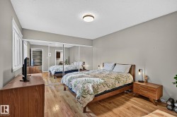 Hardwood flooring, mirrored closet doors, a rectangular window with white trim, and a flush-mount ceiling light - 