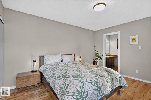 Hardwood-finish flooring, built-in closet with sliding doors, neutral wall color, built-in overhead lighting, and an attached bathroom with a vanity - 17919 78 Avenue Nw, Edmonton, AB 