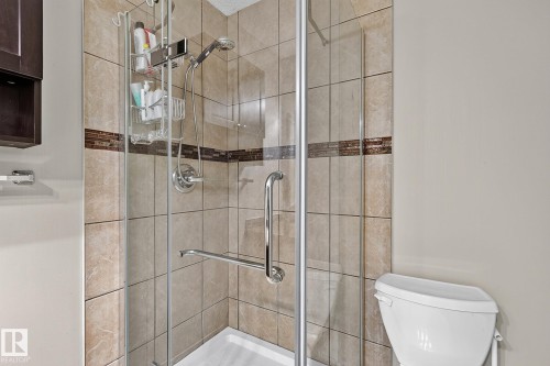 Glass-enclosed shower with tile surround, decorative tile accent band, and chrome fixtures - 17919 78 Avenue Nw, Edmonton, AB 