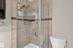 Glass-enclosed shower with tile surround, decorative tile accent band, and chrome fixtures - 