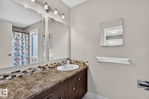 Extended vanity with an integrated sink, mosaic tile backsplash, and dark wood-finish cabinetry - 17919 78 Avenue Nw, Edmonton, AB 