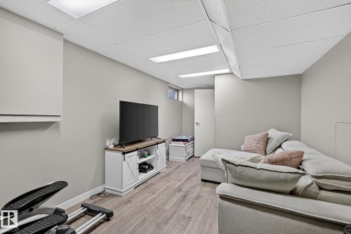 Recessed lighting, drop ceiling, wood-finish flooring, light gray walls, and a built-in media console with barn door accents - 17919 78 Avenue Nw, Edmonton, AB 