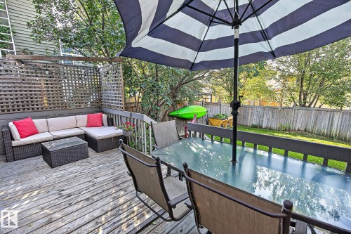 Expansive wooden deck with lattice privacy screening, a glass-top outdoor dining table, and dark-stained railing - 17919 78 Avenue Nw, Edmonton, AB 