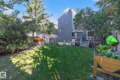 Spacious backyard with a raised garden bed, mature trees, and a wooden deck with stairs - 17919 78 Avenue Nw, Edmonton, AB 
