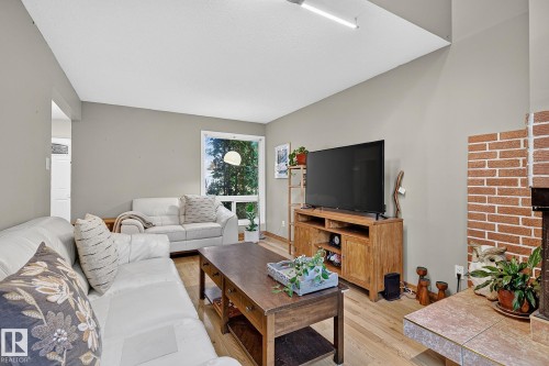 Living area featuring wood-finish flooring, a brick-surround fireplace, and an angular vaulted ceiling - 17919 78 Avenue Nw, Edmonton, AB 