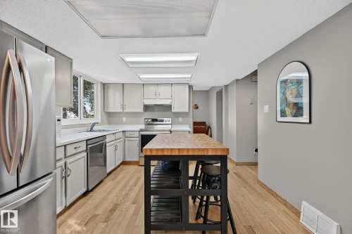 Kitchen featuring light wood-finish flooring, white cabinetry, light countertops, and stainless steel appliances - 17919 78 Avenue Nw, Edmonton, AB 