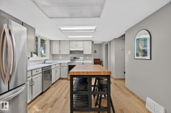 Kitchen featuring light wood-finish flooring, white cabinetry, light countertops, and stainless steel appliances - 