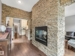 A dramatic real-stone fireplace serves as the stunning centerpiece - the grand archway creates seamless flow between the two spaces while providing natural separation when desired — allowing both sides to enjoy the warmth and ambiance of the fireplace. - 
