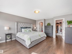 A spacious primary suite featuring his-and-hers walk-in closets and private access to a beautiful balcony overlooking the expansive backyard. - 