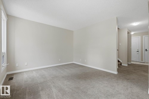 Neutral painted walls, grey carpet flooring, white trim, and a window with white casing - 10621 Beaumaris Road Nw, Edmonton, AB 