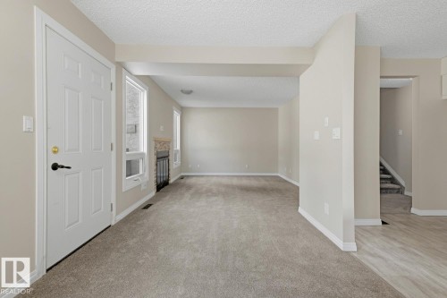 Spacious interior with neutral paint, carpeted flooring, and a decorative fireplace with a tiled surround - 10621 Beaumaris Road Nw, Edmonton, AB 