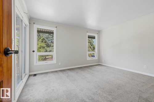 Light gray wall paint, gray carpeting, dual windows, white trim, and a wood-finish door with black hardware - 10621 Beaumaris Road Nw, Edmonton, AB 