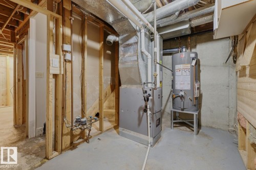Unfinished basement with concrete flooring, exposed wood framing, water heater, and furnace - 10621 Beaumaris Road Nw, Edmonton, AB 