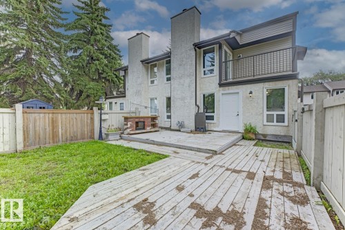 Rear exterior featuring a multi-level wood deck, a brick outdoor fireplace, and a fenced yard with mature trees - 10621 Beaumaris Road Nw, Edmonton, AB 