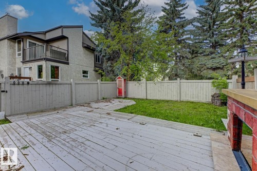 Private fenced backyard featuring a spacious wood deck, a grass lawn, and mature trees - 10621 Beaumaris Road Nw, Edmonton, AB 