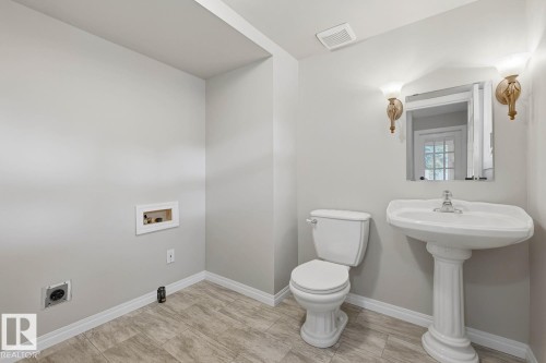 Pedestal sink with polished chrome faucet, wall-mounted mirror, and decorative sconce lighting - 10621 Beaumaris Road Nw, Edmonton, AB 